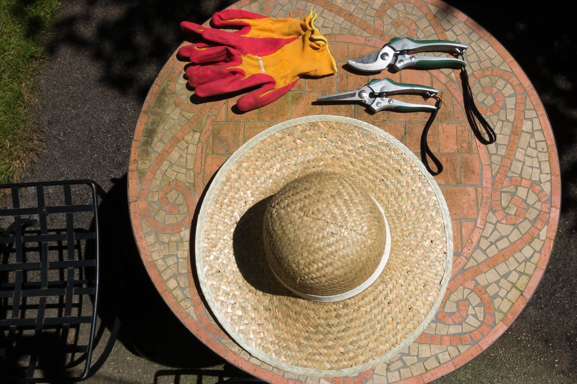 Outdoor table with wide brimmed hat, garden gloves and hand held pruners